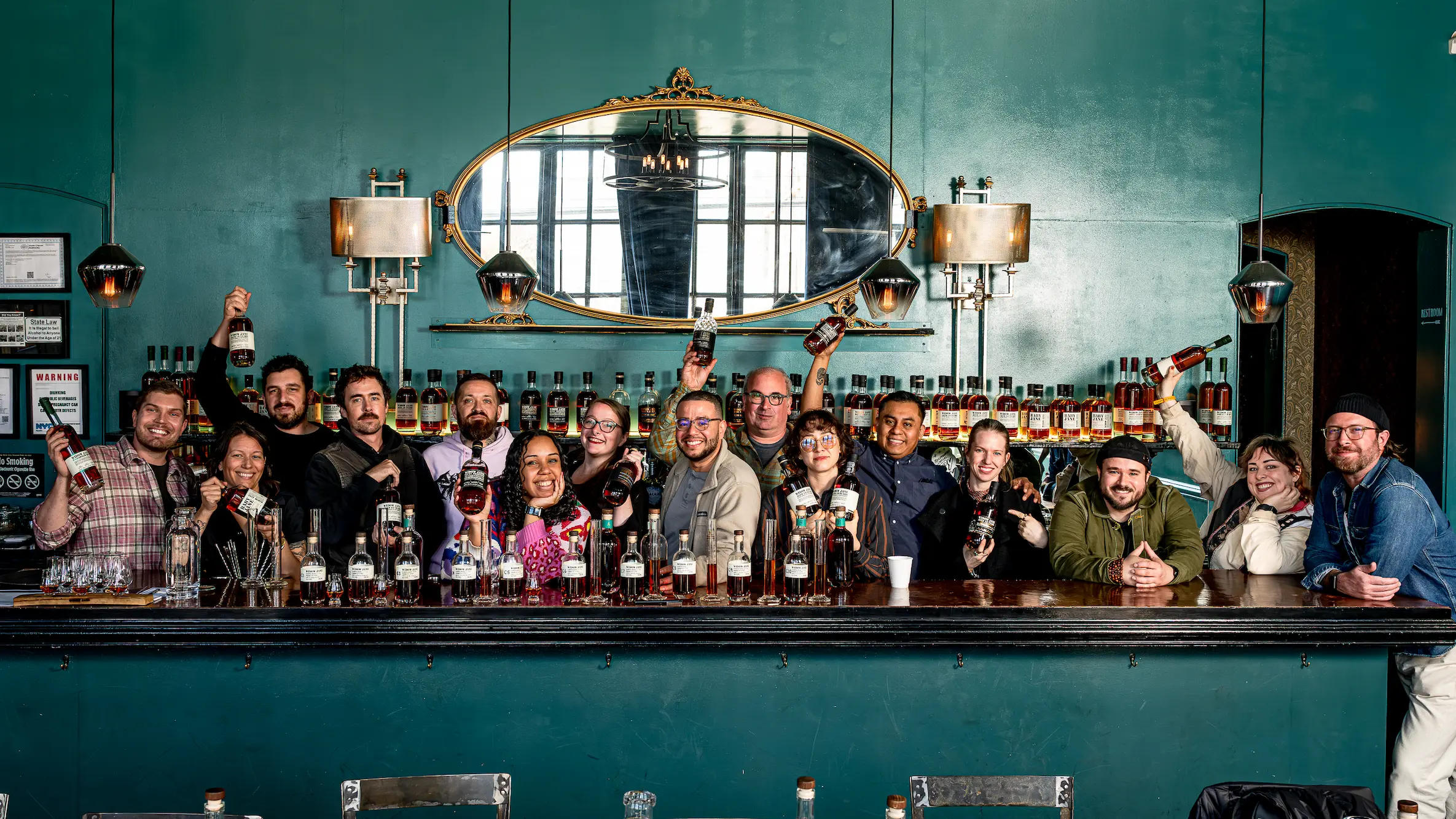 The Widow Jane team posing behind the bar holding bottles of Borough Blend